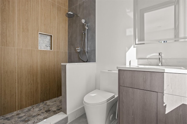 bathroom featuring vanity, a tile shower, and toilet