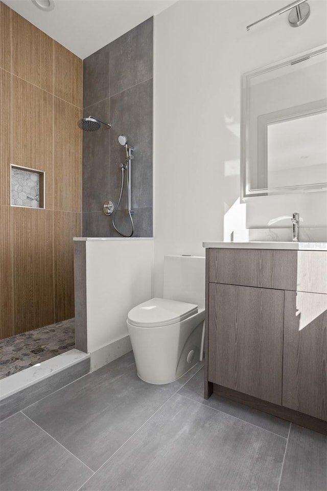 bathroom featuring vanity, tiled shower, toilet, and tile patterned floors