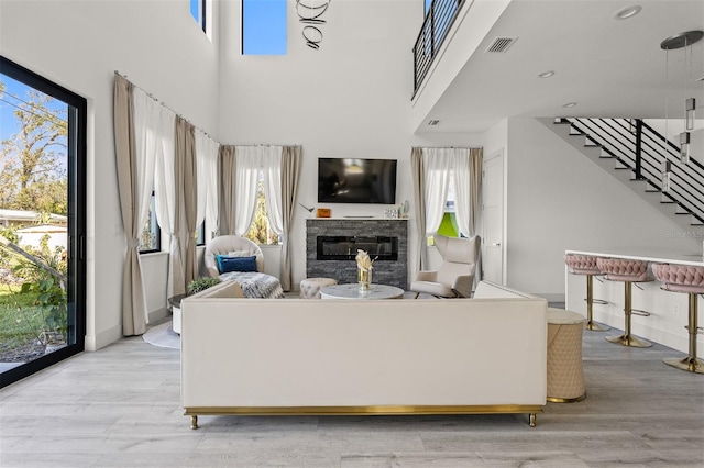 living room with a high ceiling, light wood-type flooring, and plenty of natural light