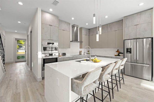 kitchen featuring modern cabinets, wall chimney exhaust hood, stainless steel appliances, and visible vents