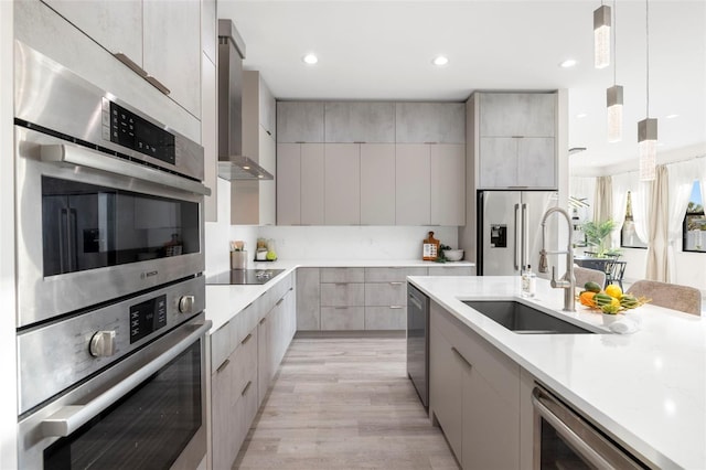 kitchen with a sink, modern cabinets, wall chimney range hood, light countertops, and appliances with stainless steel finishes