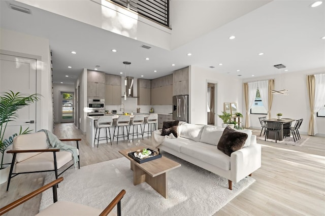 living area featuring recessed lighting, light wood-style flooring, visible vents, and plenty of natural light