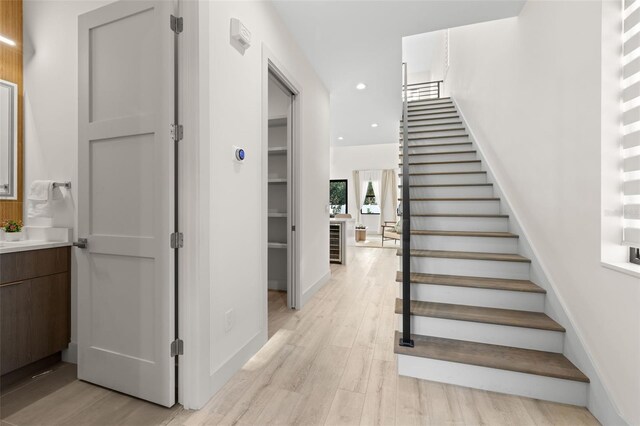stairs featuring wood finished floors and recessed lighting