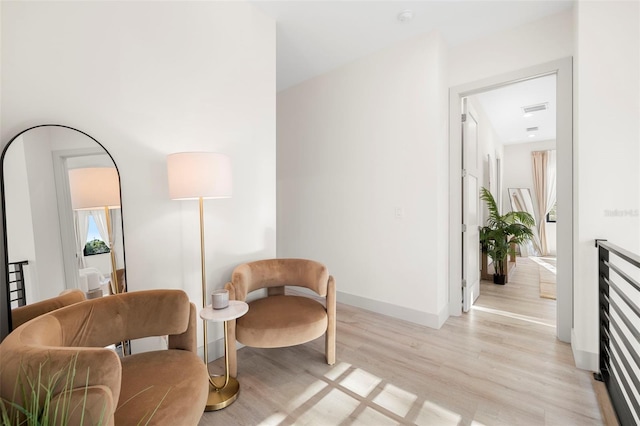 sitting room with baseboards, visible vents, and light wood finished floors