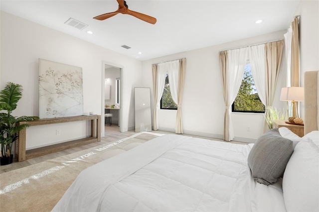 bedroom with ensuite bath, visible vents, and multiple windows