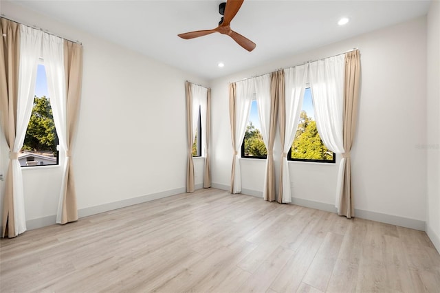 empty room with light wood-type flooring, a ceiling fan, baseboards, and recessed lighting