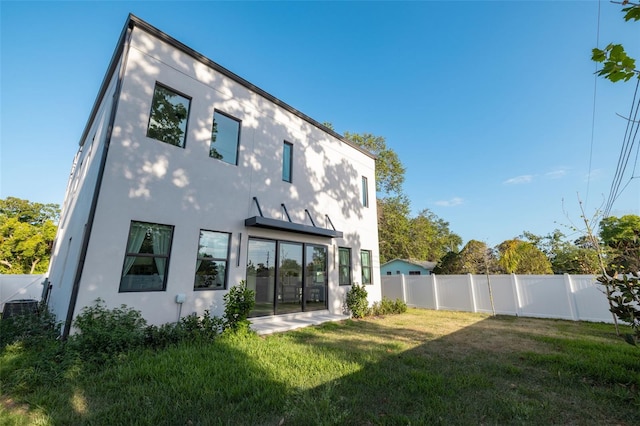 rear view of house featuring a yard, a fenced backyard, and stucco siding