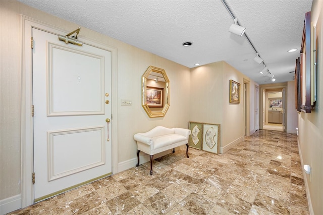 hallway with a textured ceiling and track lighting