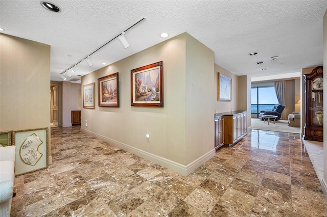 hallway with a textured ceiling and track lighting