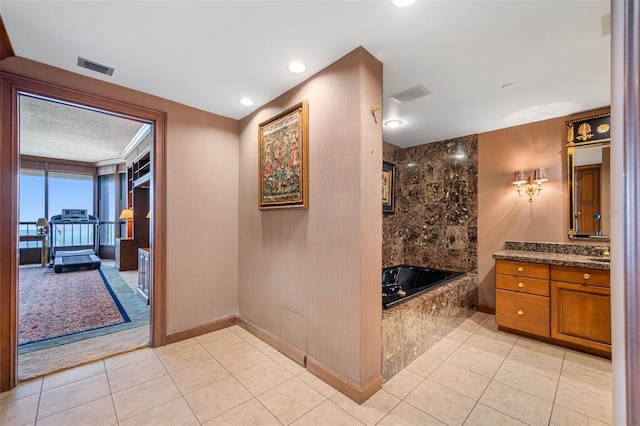 bathroom with tile patterned flooring, a washtub, and vanity