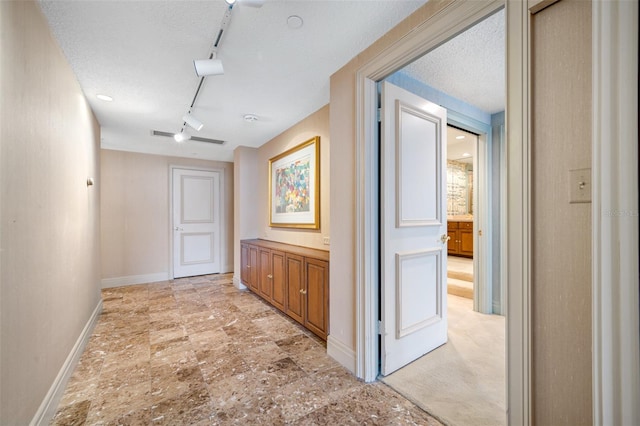 hall with a textured ceiling and track lighting