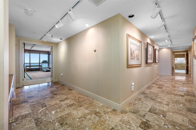 corridor with a textured ceiling and rail lighting