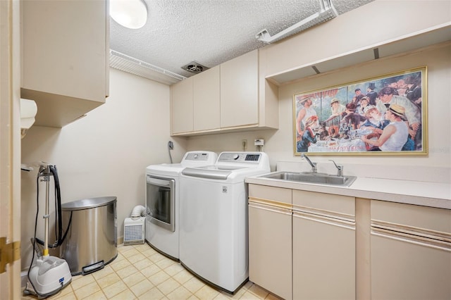 washroom featuring cabinets, a textured ceiling, washer and clothes dryer, and sink