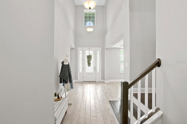 entrance foyer with light hardwood / wood-style flooring and a towering ceiling