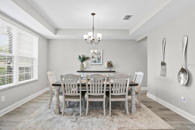 dining area featuring a notable chandelier, a tray ceiling, and hardwood / wood-style flooring