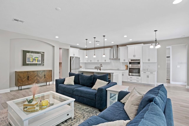 living room featuring light wood-type flooring, a chandelier, and sink