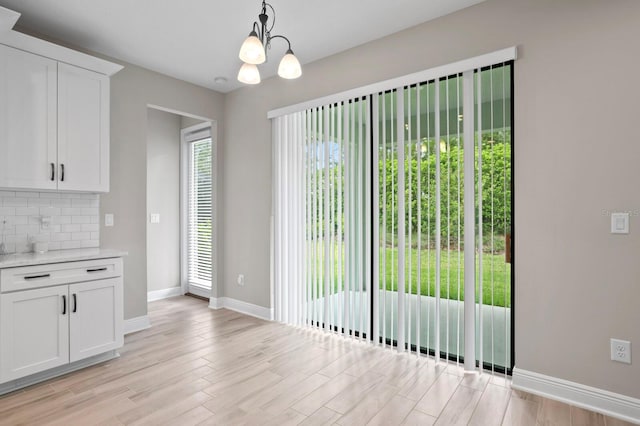 unfurnished dining area featuring a notable chandelier and light hardwood / wood-style floors