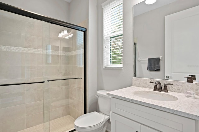 bathroom with vanity, plenty of natural light, an enclosed shower, and toilet