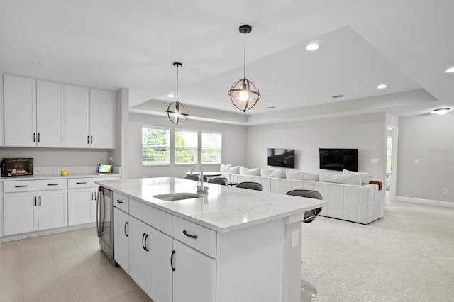 kitchen featuring a center island with sink, sink, pendant lighting, and white cabinets