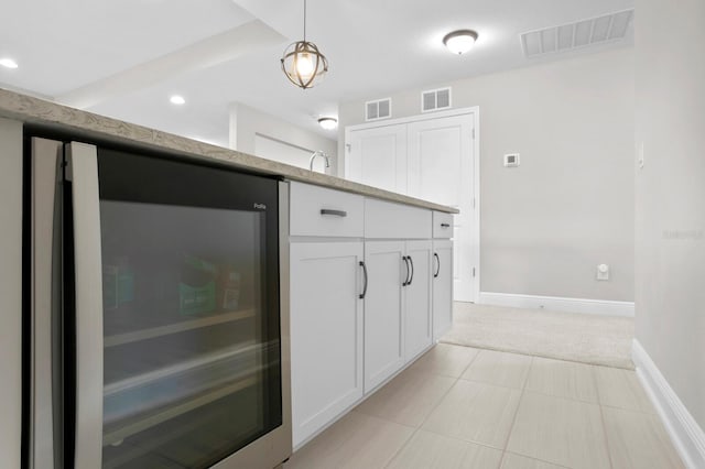 kitchen with light carpet, beverage cooler, hanging light fixtures, and white cabinetry