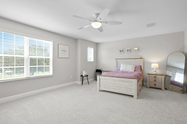 carpeted bedroom featuring ceiling fan and multiple windows