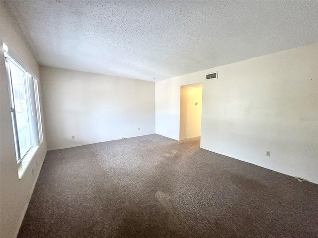 carpeted empty room featuring a textured ceiling