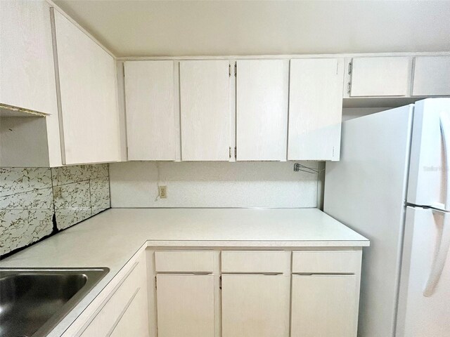 kitchen featuring white cabinets, sink, and white fridge