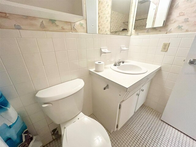 bathroom with tile walls, vanity, toilet, and tile patterned floors