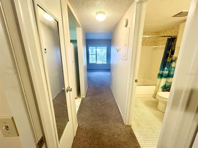 hall featuring carpet and a textured ceiling