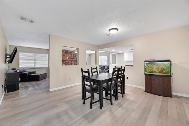 dining space with a textured ceiling and light wood-type flooring