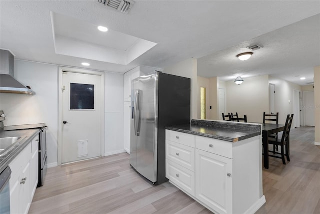 kitchen featuring stainless steel appliances, light hardwood / wood-style floors, a textured ceiling, white cabinets, and kitchen peninsula