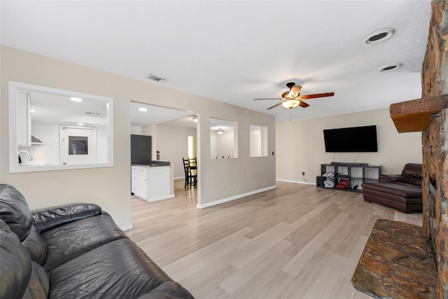 living room featuring ceiling fan and light hardwood / wood-style flooring