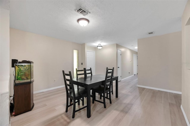 dining space with light hardwood / wood-style flooring and a textured ceiling