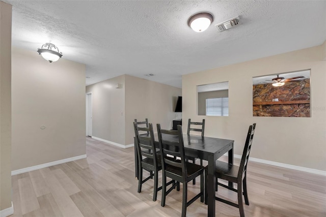 dining area featuring a textured ceiling and light wood-type flooring