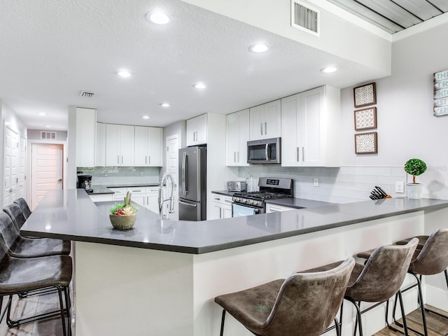 kitchen featuring white cabinets, a breakfast bar area, appliances with stainless steel finishes, and kitchen peninsula