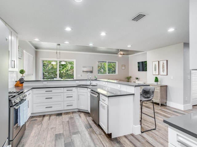 kitchen with sink, decorative light fixtures, white cabinetry, appliances with stainless steel finishes, and a kitchen breakfast bar