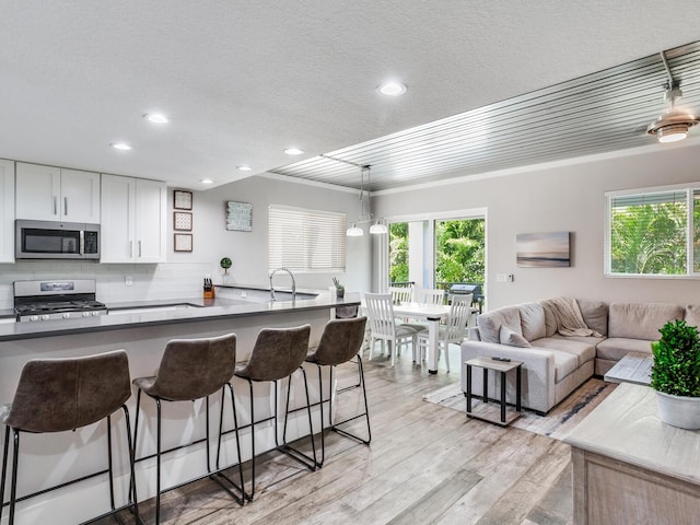 kitchen featuring range with gas stovetop, white cabinets, a kitchen bar, and hanging light fixtures