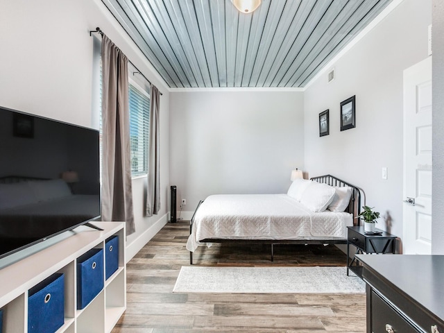 bedroom featuring ornamental molding, hardwood / wood-style floors, and wooden ceiling