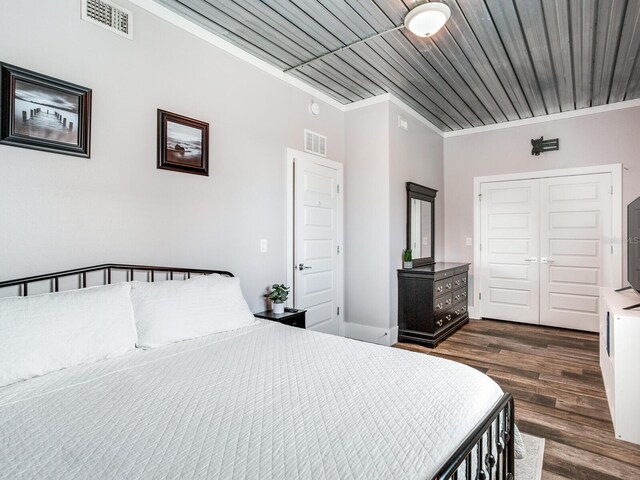 bedroom with a closet, dark hardwood / wood-style floors, crown molding, and wooden ceiling