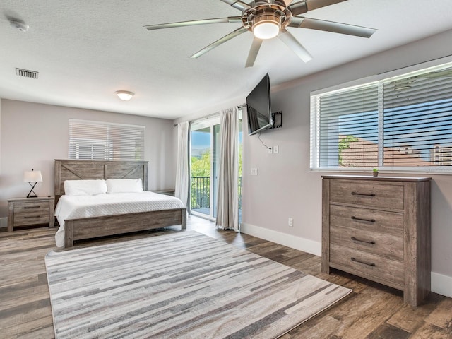 bedroom with multiple windows, ceiling fan, access to exterior, and hardwood / wood-style floors