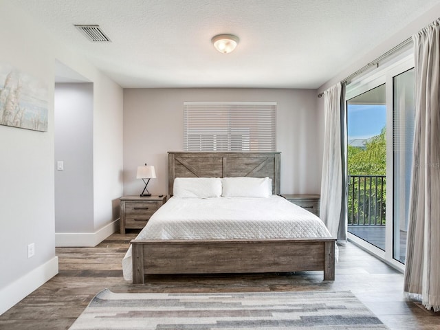 bedroom featuring hardwood / wood-style flooring, access to exterior, and a textured ceiling