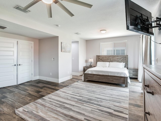 bedroom featuring ceiling fan, dark wood-type flooring, and a textured ceiling