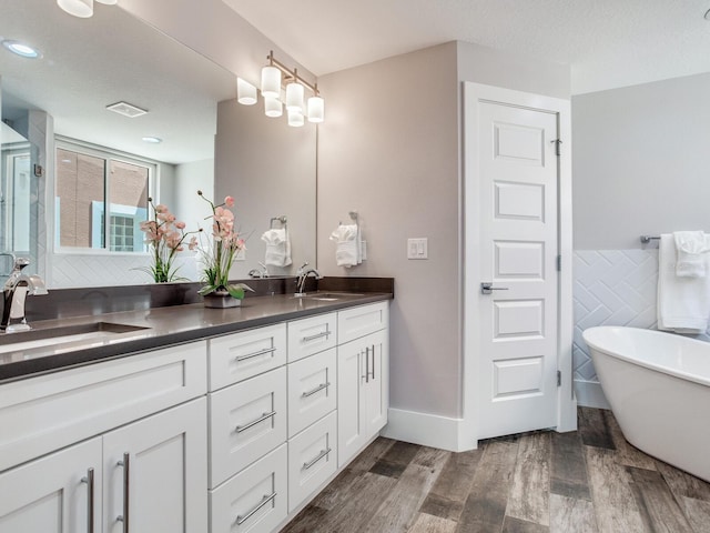 bathroom featuring vanity, wood-type flooring, a textured ceiling, plus walk in shower, and tile walls