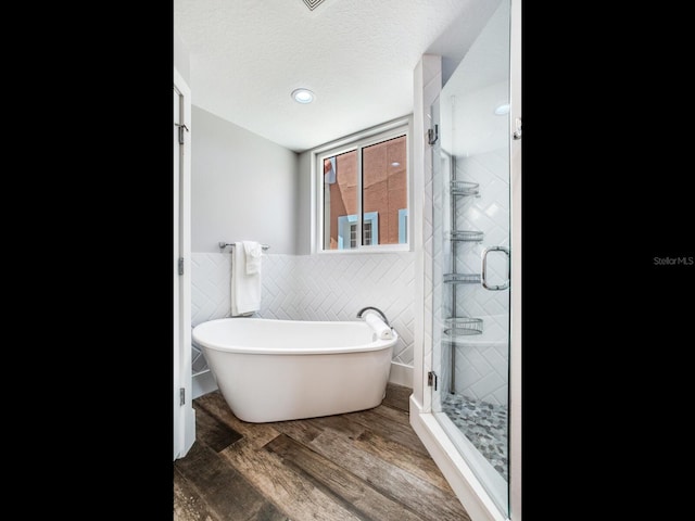 bathroom featuring wood-type flooring, a textured ceiling, independent shower and bath, and tile walls