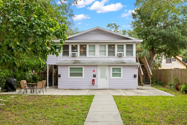 view of front of property featuring cooling unit, a front lawn, and a patio area