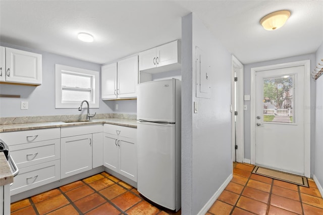 kitchen with white cabinets, white refrigerator, tile patterned flooring, and sink