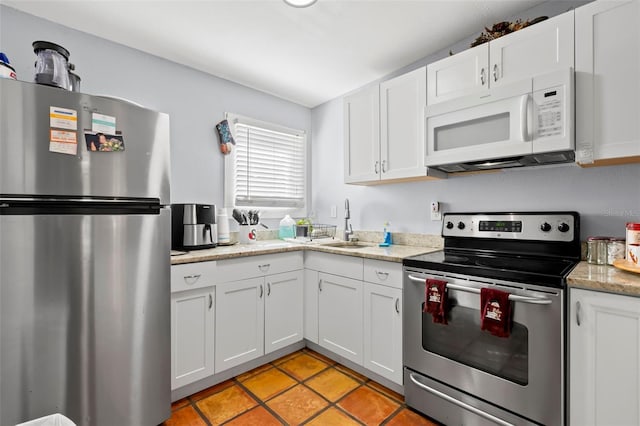 kitchen with light stone countertops, white cabinetry, sink, and stainless steel appliances