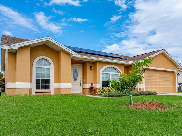 ranch-style home featuring a garage, solar panels, and a front yard