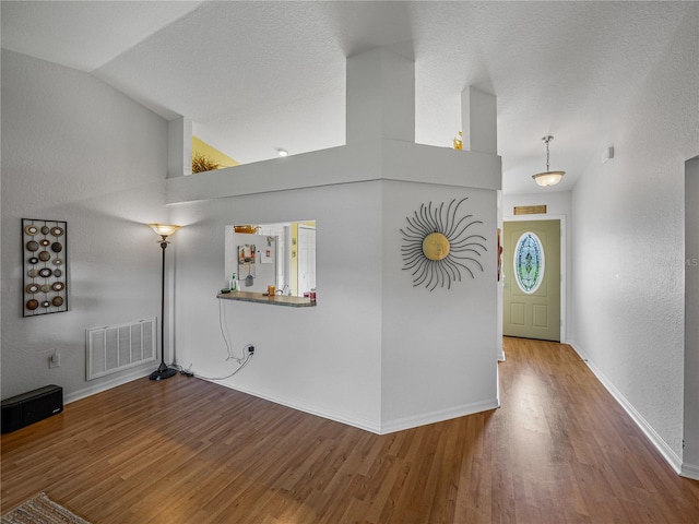 interior space featuring vaulted ceiling, a textured ceiling, and hardwood / wood-style flooring