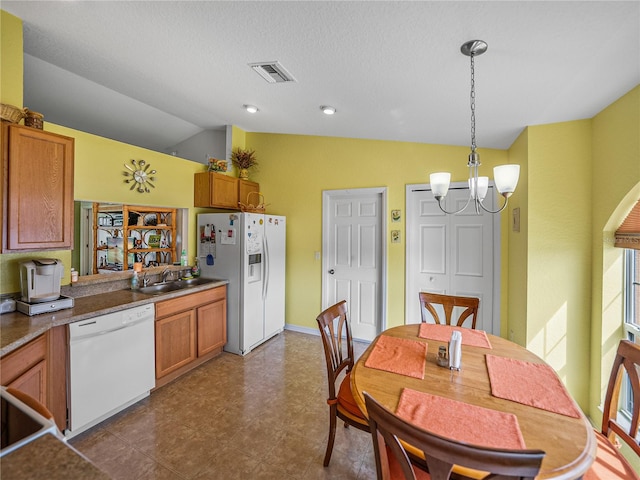 kitchen with pendant lighting, sink, a notable chandelier, lofted ceiling, and white appliances